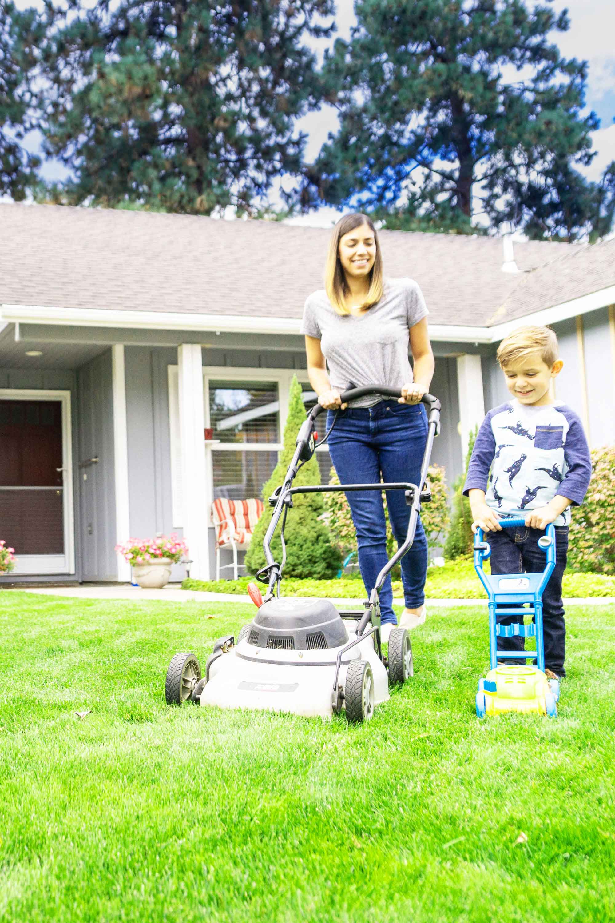 Mom and son mowing lawn in front of house