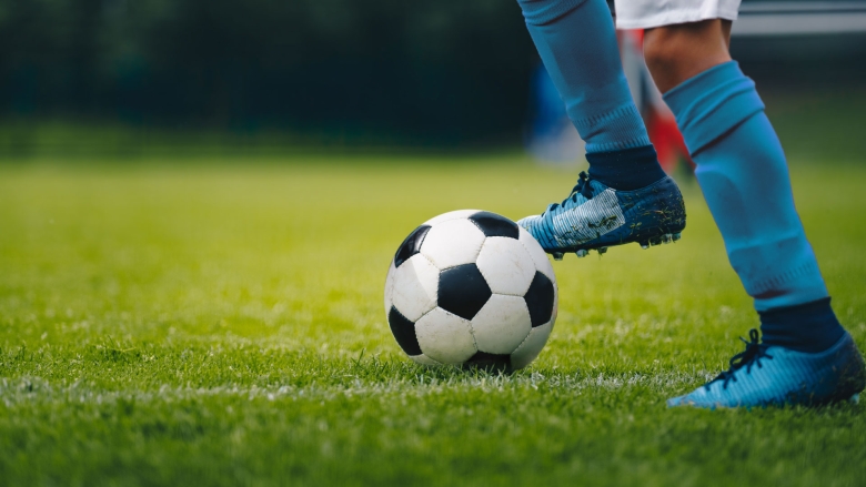 Soccer cleats on green grass with soccer ball