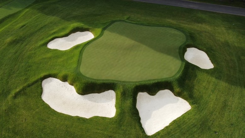 Aerial view of a golf course with sand traps and bunkers lining a raised green
