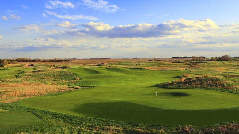 Rolling golf course green with blue sky and clouds 
