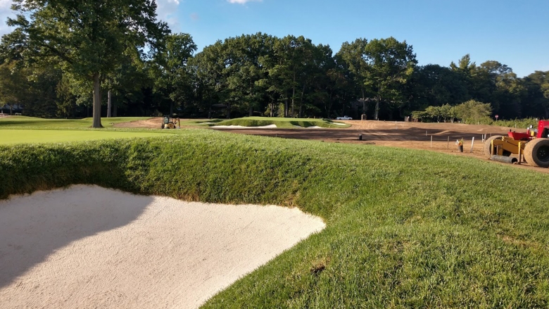 Closeup of a golf bunker face with trees, blue sky in background 