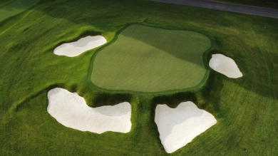 Aerial view of a golf course with sand traps and bunkers lining a raised green