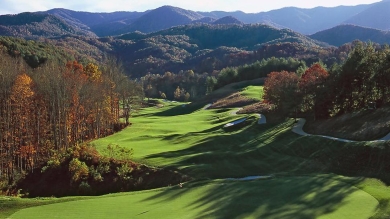 Aerial view of a golf course with autumn trees lining the fairway 