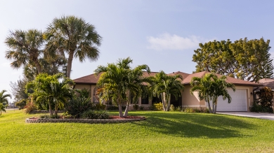 Single level house with palm trees and grass lawn