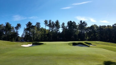 Golf course with green grass and trees in the background with blue sky