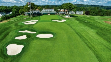Green golf course with clubhouse in the background. 