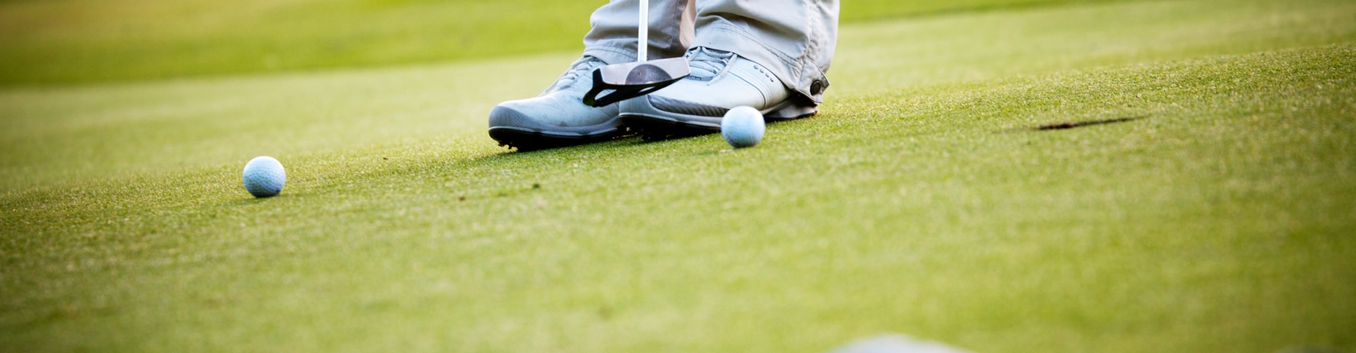 two golf balls on golf course green with flag in foreground