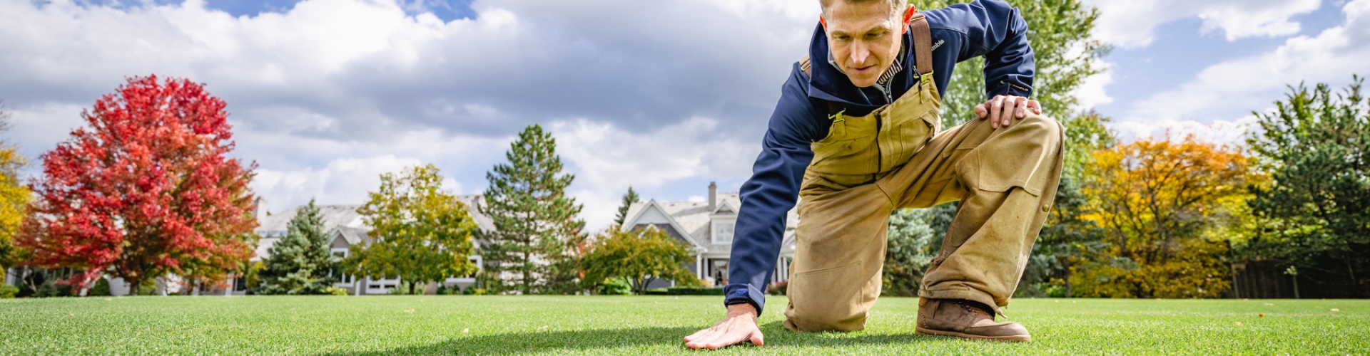 man kneeling on golf course feeling grass
