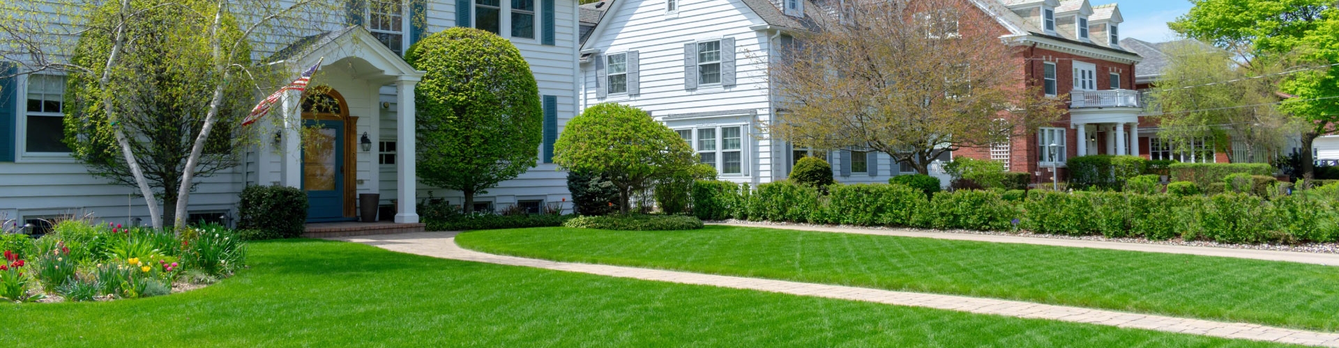 White, two story houses with green, lush lawn.
