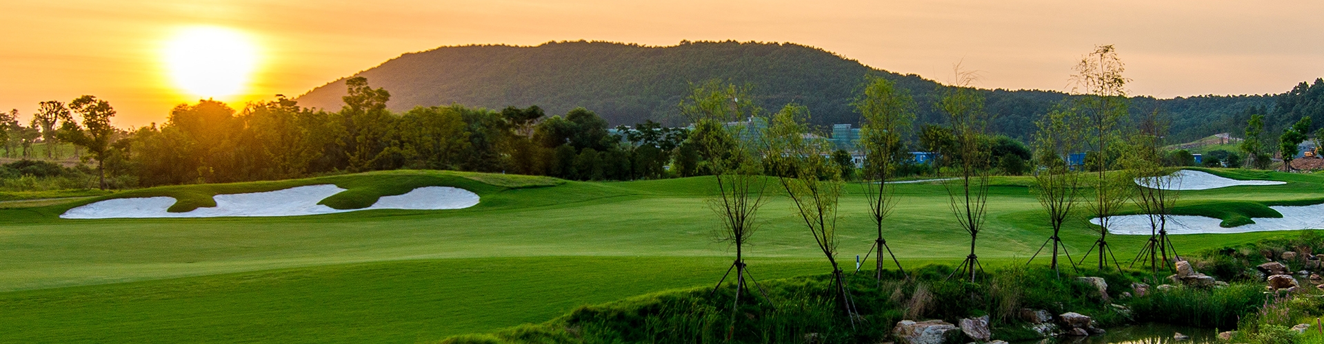 Golf course with a hill and setting sun in background