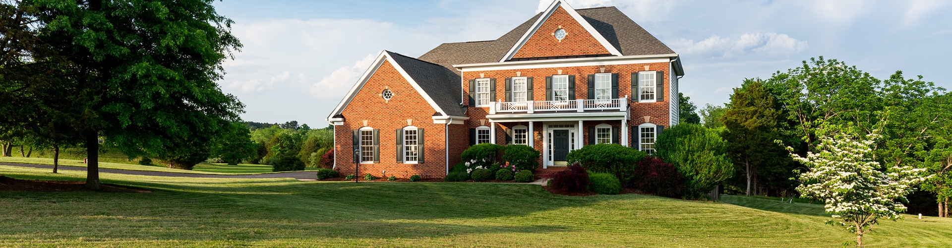 Landscape photo of a brick house with green grass 