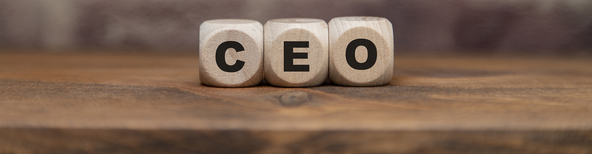 Closeup of wooden blocks with the letters CEO against a blurred brick background