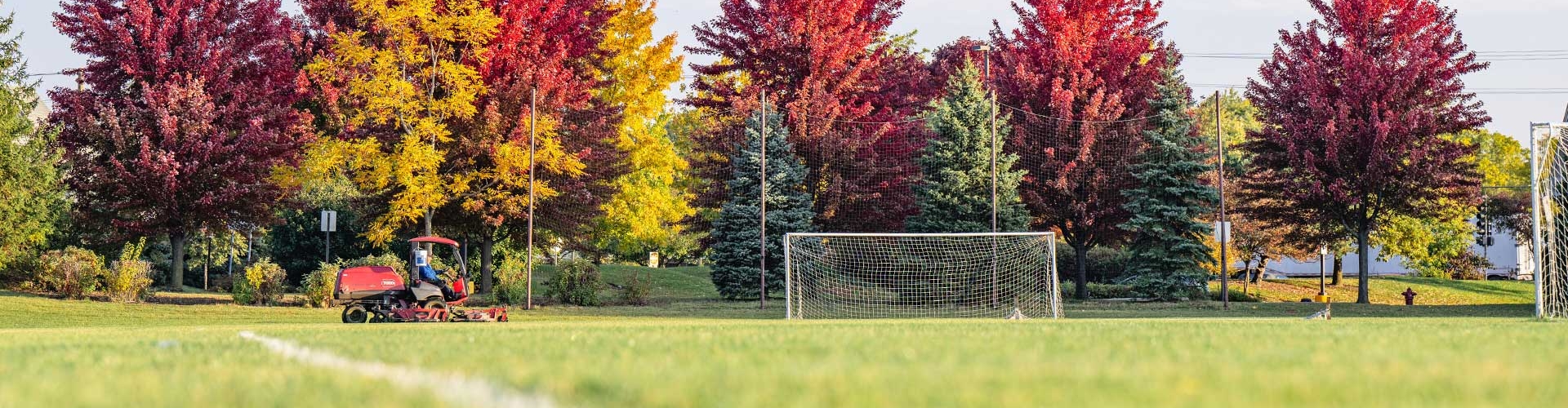 Soccer field with fall color trees in background.
