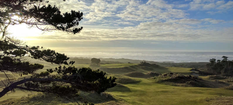 Golf course on the coast under a cloudy sky.