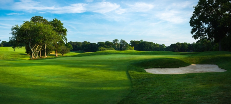 Pristine green fairway and rough on a golf course under a blue sky