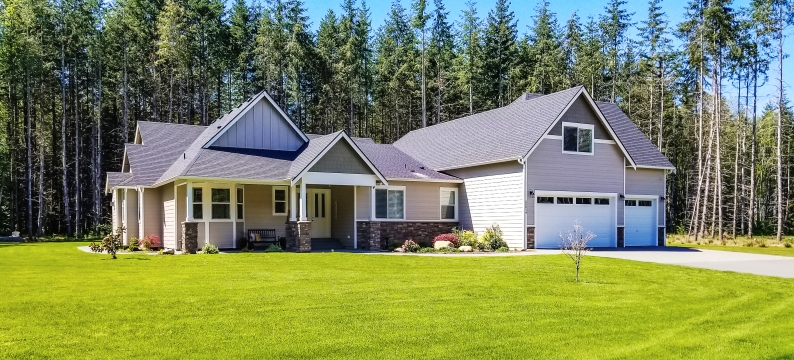 Nice newer home with large flat front yard and trees in the background