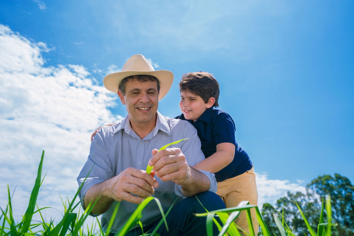 Father and son in a field looking at grass seed 
