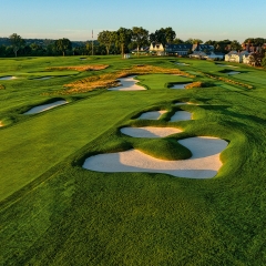Green golf bunkers at sunset with the golf course clubhouse in the background 